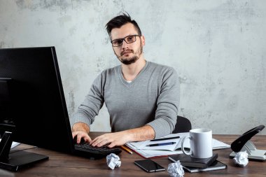 Bir bilgisayarda çalışan bir erkeğin, ofiste, bir masada oturan bir adam. Ofis işleri kavramı. Kopya alanı.