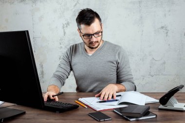 Bir bilgisayarda çalışan bir erkeğin, ofiste, bir masada oturan bir adam. Ofis işleri kavramı. Kopya alanı.