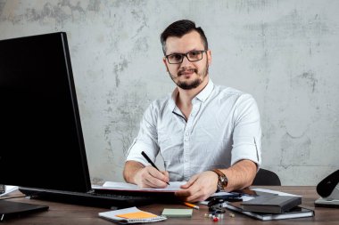 Önemli evraklar üzerinde çalışan bir erkeğin, ofiste, bir masada oturan bir adam. Ofis işleri kavramı. Kopya alanı.