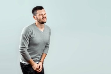 Genç, çekici bir adam onun kasık, bacaklarının arasında katlanmış silah ağrı hissediyor. Karşılaşan ağrı, Erkek sorunları, kudret.
