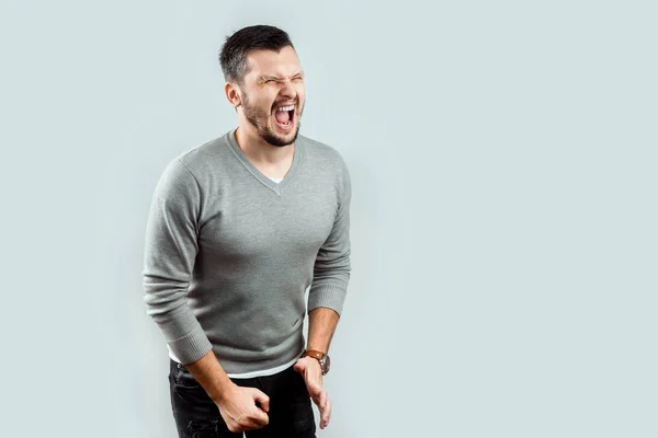 A young, attractive man feels pain in his groin, arms folded between his legs. Experiencing pain, male problems, potency. — Stock Image Young Attractive Man Feels Pain His Groin Arms Folded His Stock Picture
