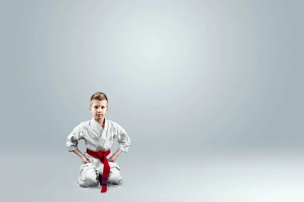 Creative background, baby in white kimono on a light background. The concept of martial arts, karate, sports since childhood, discipline.