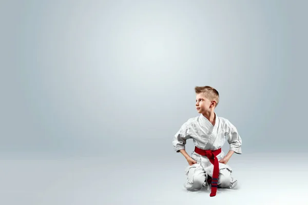 Creative background, baby in white kimono on a light background. The concept of martial arts, karate, sports since childhood, discipline.