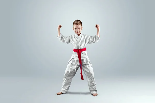 Creative background, a child in a white kimono in a fighting stance, on a light background. The concept of martial arts, karate, sports since childhood, discipline, first place, victory. copy space.