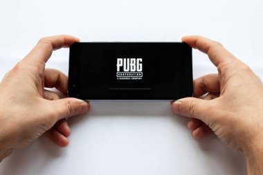 Brest, Belarus, January 22, 2019. Closeup male hands holding smartphone with PUBG FPS game. battleground game logo. Soft focus. clipart