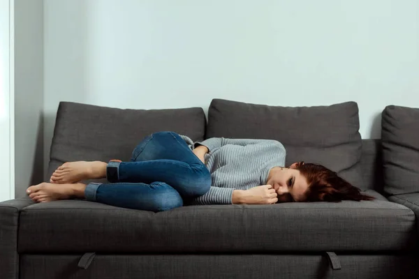 年轻美丽的女孩患有胃痉挛和腹痛 躺在家里的沙发上 女性月经 胃痉挛的概念 — 图库照片