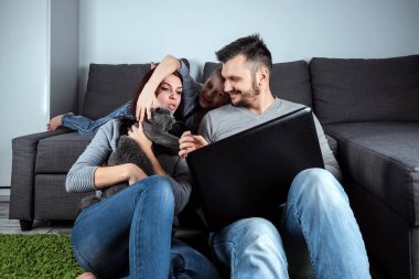 Mutlu bir aile ile bir laptop bir şey izlerken gülümsüyor. Ortak eğlence, tatil, ortak dinlenme, aile ilişkileri kavramı.