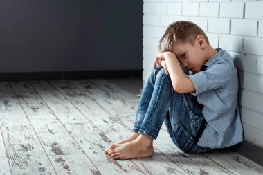 Genç bir çocuk üzgün bir duygu ile duvarın yanında okulda tek başına oturur. Rahatsız çocuk koridorda terk etti ve bir tuğla duvara bükülmüş. Zorbalık, ayrımcılık kopya alanı ile.
