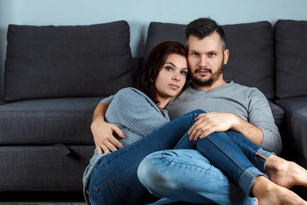 Retrato Una Hermosa Pareja Joven Mirando Cámara Contra Sofá Gris —  Fotos de Stock