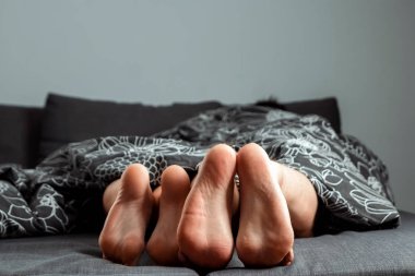 Bacaklarda, aşık bir çiftin ayakları battaniyenin altından çıkıyor. Sevgililer günü veya aşk hikayesi. Prelude yatakta, seks, yetişkin siteleri, aşk, ilişkiler.