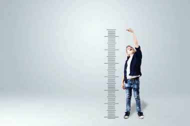 A boy on a white background shows how he grew up, dreams of becoming an adult. The concept of big growth, business, maturing. clipart