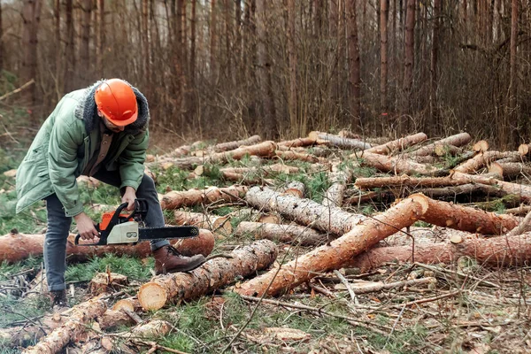 Loggning, arbetare i en skyddande dräkt med en motorsåg sågning trä. Skära ner träd, skogförstörelse. Begreppet industriell förstörelse av träd, vilket skadar miljön. — Stockfoto