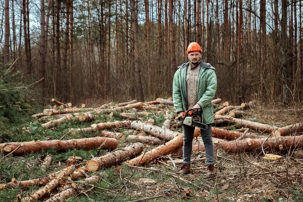 Logging, trabalhador num fato de protecção com uma motosserra. Cortar árvores, destruição florestal. O conceito de destruição industrial de árvores, causando danos ao meio ambiente . — Fotografia de Stock