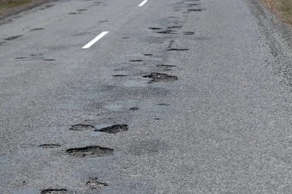 El camino en mal estado con muchos baches. Los coches van con el riesgo de averías . — Foto de Stock