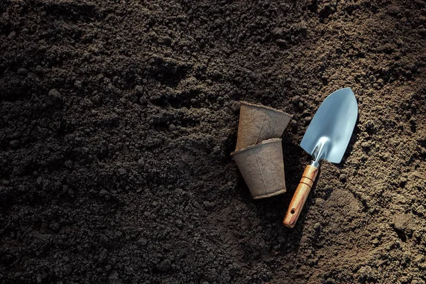 Pentole per piantine e una piccola spatola a terra. Il concetto di giardino, l'inizio della stagione, cottage estivo . — Foto Stock