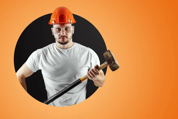 Bearded Man in a helmet holds a sledgehammer on an orange background. Concept of construction, contractor, repair. — Stock Photo, Image
