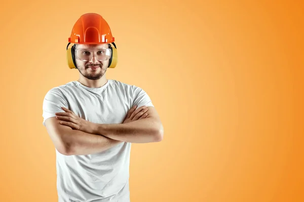 Mannelijke bouwer in oranje helm op een oranje achtergrond. Concept bouw, aannemer, herstelling. — Stockfoto