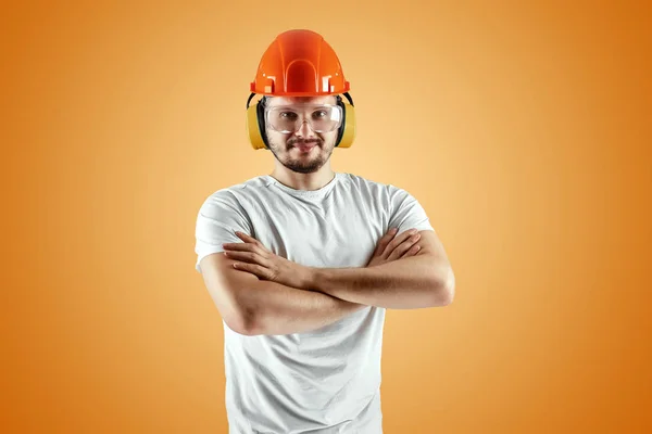 Mannelijke bouwer in oranje helm op een oranje achtergrond. Concept bouw, aannemer, herstelling. — Stockfoto