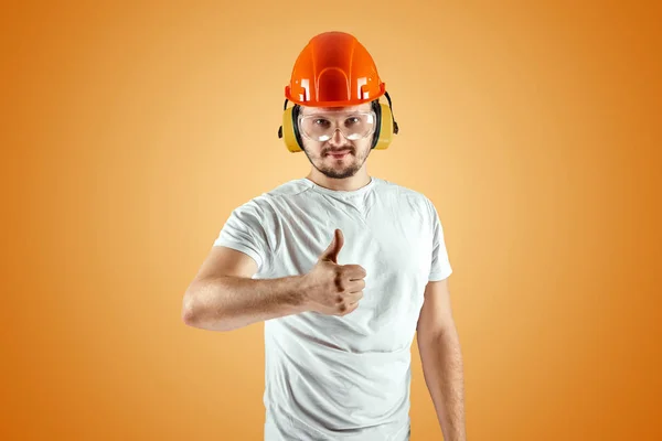 Férfi építője narancssárga sisakot narancssárga háttérrel. A konstrukció fogalma, vállalkozó, javítás. — Stock Fotó