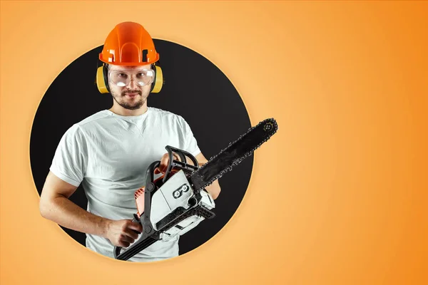 Szakállas férfi sisakot tart láncfűrész narancssárga háttérrel. Építési koncepció, vállalkozó, javítás, Favágó. — Stock Fotó