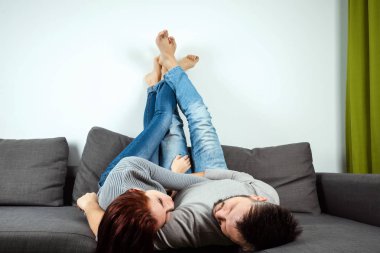 Sevgi dolu bir çift evde bir yatakta yatarken, bacaklarını yukarı kaldırarak, tembel bir aile bir hafta sonu istirahat, kopya alanı.