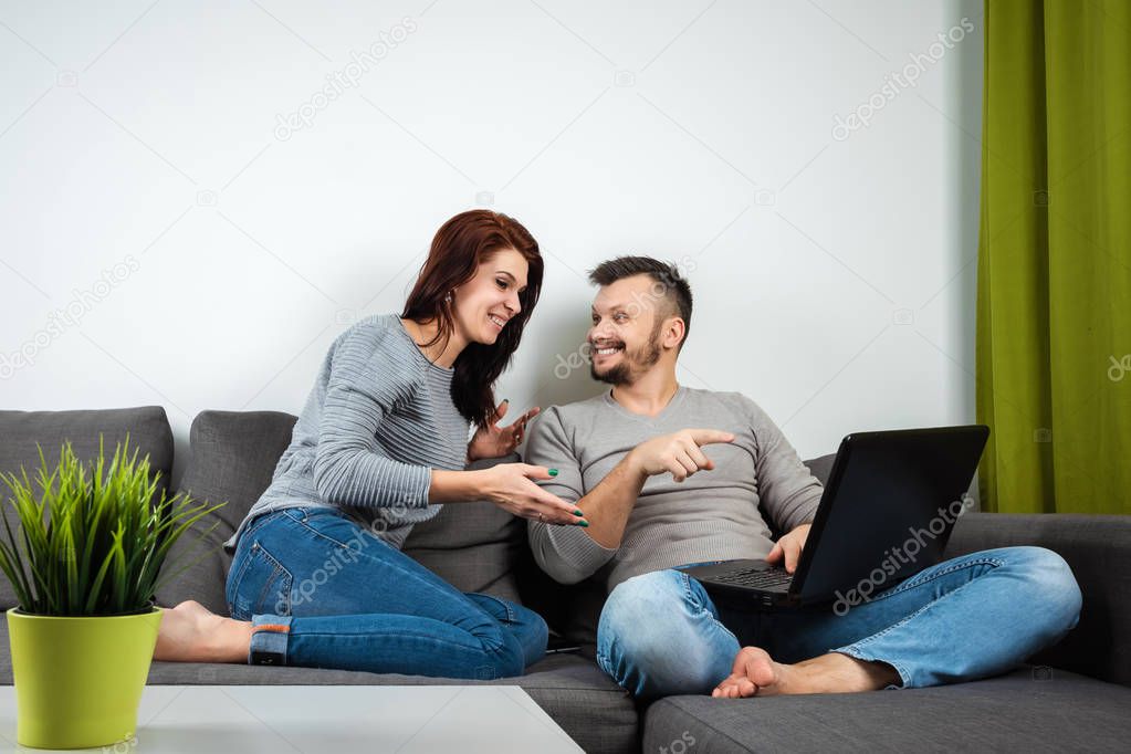 The girl and the guy have fun in two for the laptop. The concept of family relationships, watching movies together, sharing time.