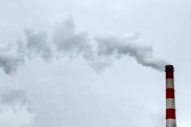 Dumanın gri gökyüzüne değdiği boru. Hava kirliliği, CO2, karbondioksit gazı, egzoz gazı kavramı.