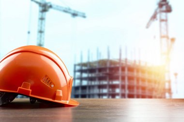 İnşaatın arka planında portakal yapımı kask yakın çekim. Mimarlık, inşaat, mühendislik, tasarım kavramı. Kopyalama alanı.