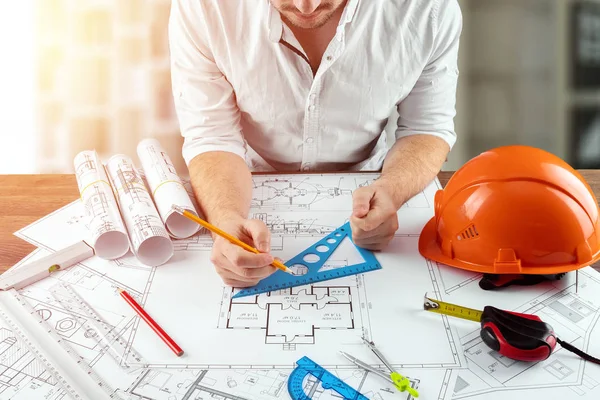 Engineer architect for a stolos with architectural construction drawings. The architect is working on the drawings. The concept of architecture, construction, engineering, design. Copy space. — Stock Photo, Image