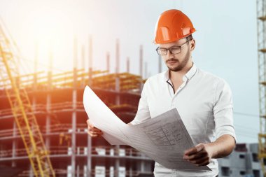 Müteahhit, mimar elinde şantiye nin arka planında mimari çizimler tutar. Konsept mimarlık, inşaat, mühendislik, tasarım, onarım. Kopyalama alanı