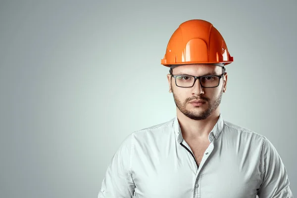 Портрет чоловіка в будівлі помаранчевого шолома на світлому тлі. Концепція архітектури, будівництва, інженерії, дизайну, ремонту. Копіювати простір — стокове фото
