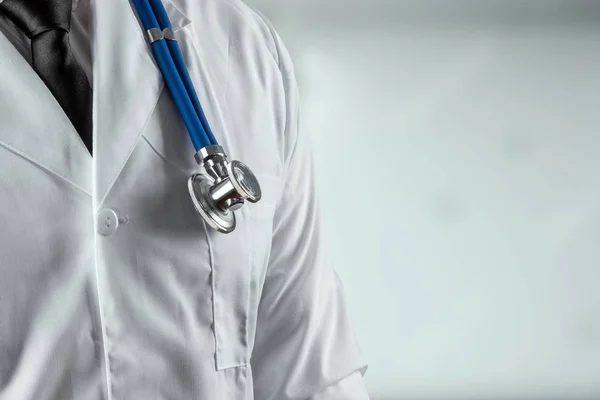 Un hombre, un médico con una bata blanca y un estetoscopio. El concepto de medicina, una cita con el médico, atención médica. Copiar espacio . — Foto de Stock