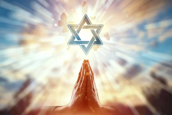 Mãos fechadas sobre o fundo do símbolo do judaísmo, oração, a estrela de David, um bando de borboletas voa. Judaísmo, o conceito de esperança, fé, religião, um símbolo de esperança e liberdade . — Fotografia de Stock