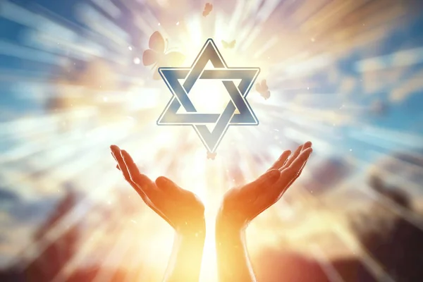 Yahudiliğin sembolünün arka planında yakın eller, dua, Davud'un yıldızı, kelebek sürüsü sinekler. Yahudilik, umut kavramı, inanç, din, umut ve özgürlük sembolü. — Stok fotoğraf