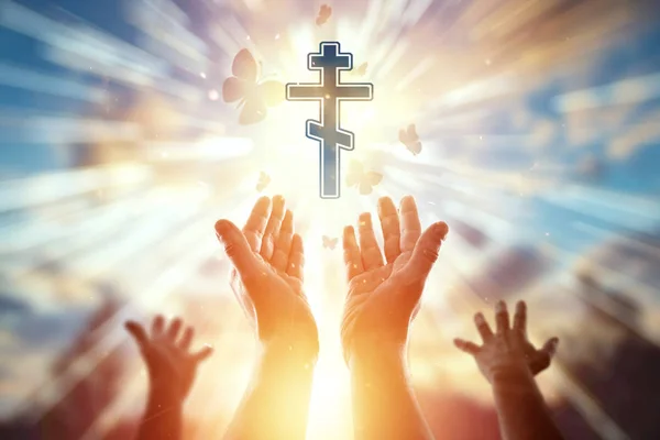 Ruce se obléšlí na pozadí symbolu křesťanství, modliteb, pravoslavného kříže. Pojem náboženství, naděje, víra, symbol svobody. — Stock fotografie