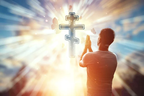 Homem no fundo do símbolo do cristianismo, oração, cruz ortodoxa no fundo do pôr do sol. O conceito de esperança, fé, religião, um símbolo de liberdade . — Fotografia de Stock