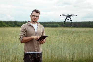 Erkek bir çiftçi tarım arazisi üzerinde insansız hava aracı nı yönetir. Teknoloji, verimliliği artırmak için yenilik, modern tarım.