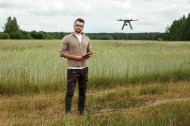Erkek bir çiftçi tarım arazisi üzerinde insansız hava aracı nı yönetir. Teknoloji, verimliliği artırmak için yenilik, modern tarım.