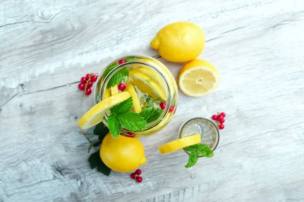 Homemade lemonade with fresh lemons, mint and cranberries. A can of lemonade on a white wooden background. The concept of fresh lemonade, cold juice, heat — Stock Photo, Image