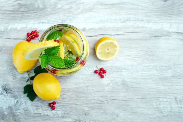 Homemade lemonade with fresh lemons, mint and cranberries. A can of lemonade on a white wooden background. The concept of fresh lemonade, cold juice, heat — Stock Photo, Image