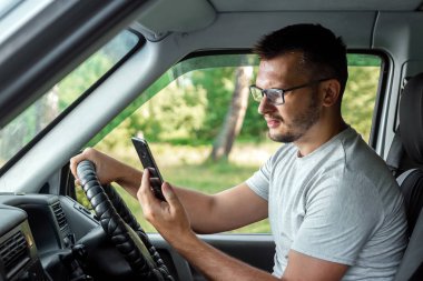 Direksiyonda elinde akıllı telefon tutan bir adam trafik kurallarını çiğniyor. Kaza konsepti, trafik ihlali, direksiyondaki telefon.