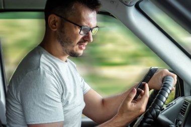 Direksiyonda elinde akıllı telefon tutan bir adam trafik kurallarını çiğniyor. Kaza konsepti, trafik ihlali, direksiyondaki telefon.