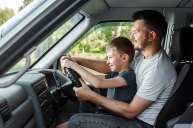 Baba, küçük oğluna yolda araba sürmeyi öğretir. Ebeveynler ve çocuklar, baba ve oğul