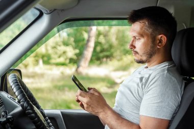 Direksiyonda elinde akıllı telefon tutan bir adam trafik kurallarını çiğniyor. Kaza konsepti, trafik ihlali, direksiyondaki telefon.