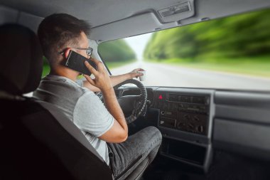 Direksiyonda elinde akıllı telefon tutan bir adam trafik kurallarını çiğniyor. Kaza konsepti, trafik ihlali, direksiyondaki telefon.