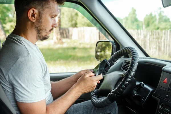 Muž za volantem, držící v ruce smartphone, porušuje dopravní předpisy. Koncept nehody, narušení provozu, telefon za volantem — Stock fotografie