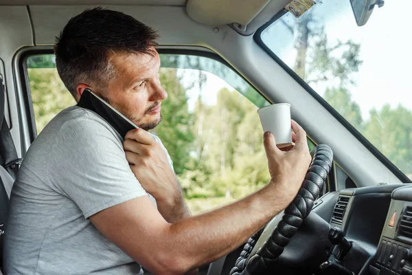 Muž za volantem, držící v ruce smartphone, porušuje dopravní předpisy. Koncept nehody, narušení provozu, telefon za volantem — Stock fotografie