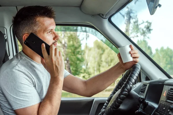 Muž za volantem, držící v ruce smartphone, porušuje dopravní předpisy. Koncept nehody, narušení provozu, telefon za volantem — Stock fotografie