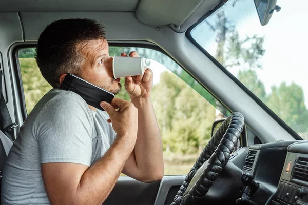 Muž za volantem, držící v ruce smartphone, porušuje dopravní předpisy. Koncept nehody, narušení provozu, telefon za volantem — Stock fotografie