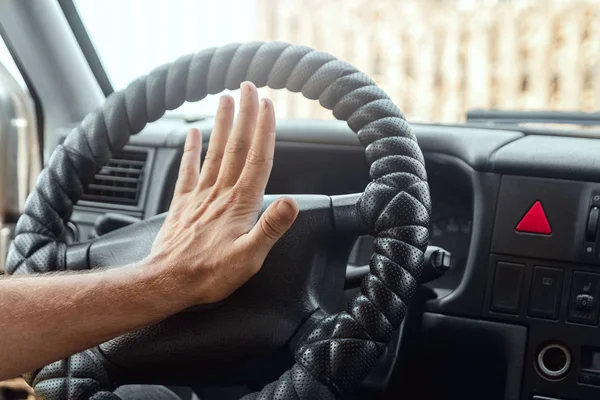 Male hand presses the signal on the steering wheel of the car. Close-up. Emergency, accident, traffic violation